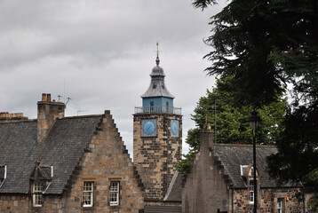 Old Stone Clock Tower seen Above Roofs of Old Buildings