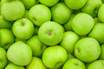 A lot of ripe green apples at market shelf.