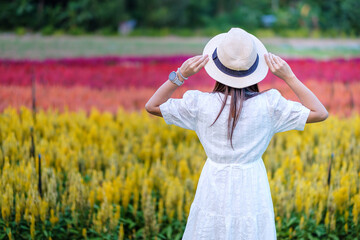 Happy tourist woman in white dress enjoy beautiful Flowers garden. travel, nature, vacation and holiday concept