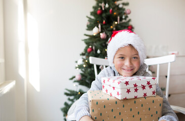 Happy boy in santa clause hat with Christmas gifts