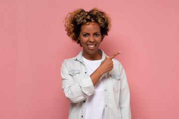 African American woman with sad grimace, points thumb aside, expresses regret emotions.