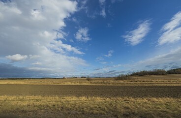 Beautiful nature landscape view on spring day. Plowed field merging with blue sky and white clouds....