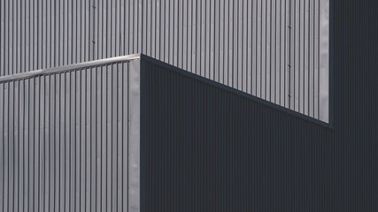 Fototapeta na wymiar Sunlight and shadow on surface of gray corrugated metal factory building wall in perspective view