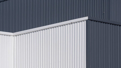 Fototapeta na wymiar Low angle and side view of gray and white corrugated metal factory building wall in perspective view