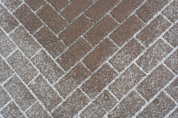 The first snow on the tile-paving stones, the material is an abstract background.