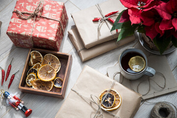 Dry orange circles in a wooden box made of mango wood, wrapped in craft paper and tied with twine, gifts, a mug with tea with lemon. Preparing for Christmas.