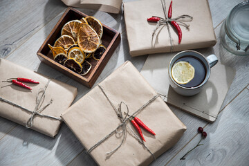 Dry orange circles in a wooden box made of mango wood, wrapped in craft paper and tied with twine, gifts, a mug with tea with lemon. Preparing for Christmas.