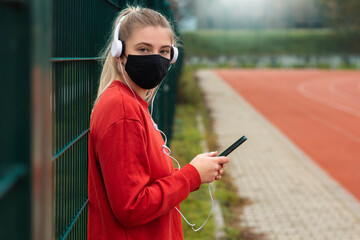Young female runner is having break and listening to music during the run