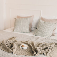 Cup of coffee with warm plaid. Breakfast in bed. White stylish cozy bedroom. Hygge concept. Copy space. Flat lay, top view.