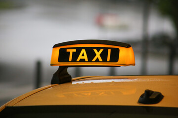 Taxi sign on yellow cab on rainy day