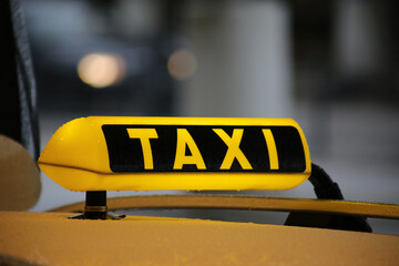 Taxi sign on yellow cab on rainy day