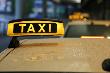 Taxi sign on yellow cab on rainy day