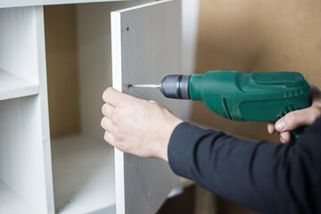 The master holds a puncher in his hands and drills a hole. Power tool rental concept. Furniture manufacturing