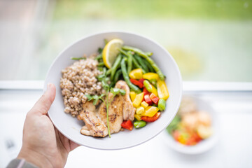 Hand holding a chicken and buckwheat dish with green beans