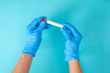 hand in blue gloves holding a test tube