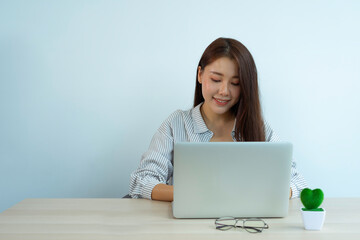 An Asian female finance worker checks data from a laptop. That shows the company's profitability report To keep the information presented to her boss, performance audit ideas, and financial business.