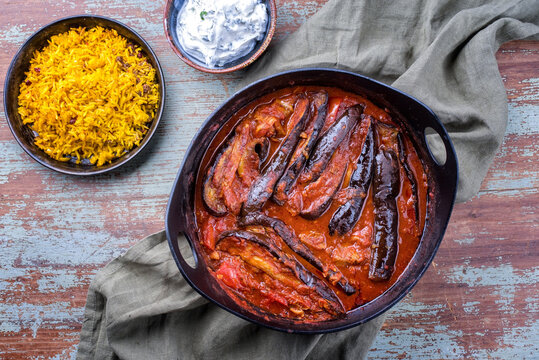 Modern style slow cooked Persian lamb eggplant stew khoresh bademjan served with rice and yoghurt as top view in a design pot