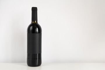 Black bottle of red wine on a white background with copy space. Wine mockup on the table