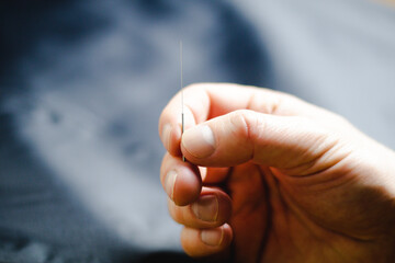 close up of a hand holding an acupuncture needle vertically