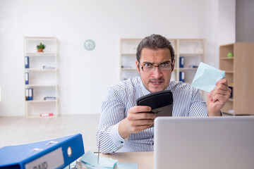 Obraz premium Young male bookkeeper calculating tax payments in the office