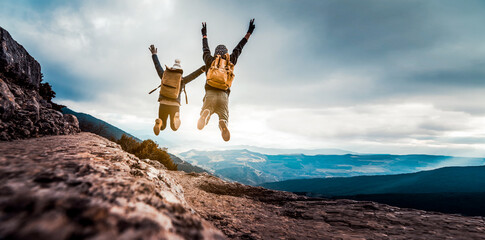 Successful hikers jumping on the top of the mountain - Happy couple with backpack enjoying life at...