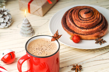 Red cup with cappuccino and cinnamon bun. Cozy home.
