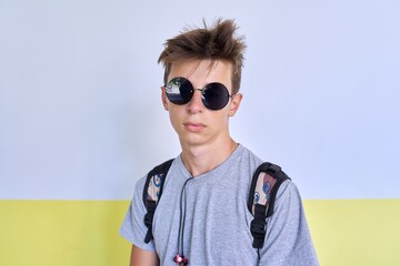 Portrait of teenager student guy 16, 17 years old in fashionable sunglasses