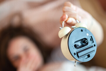 Sleeping Concept;Beautiful woman face with blur.
Woman hand holding alarm clock.