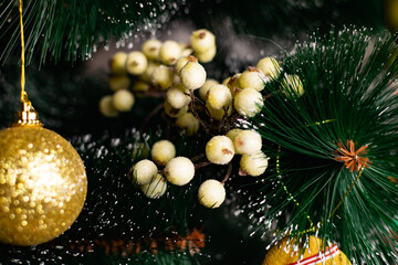 Fototapeta na wymiar Golden Christmas decorations on a green artificial Christmas tree. Making a festive Christmas. Funny cute toys and gifts on the branches