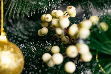 Golden Christmas decorations on a green artificial Christmas tree. Making a festive Christmas. Funny cute toys and gifts on the branches