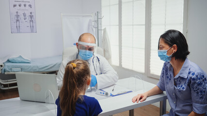 Obraz premium Doctor with protective gloves showing skeleton on tablet to girl. Physician specialist in medicine providing health care services consultation treatment examination in hospital cabinet during covid-19