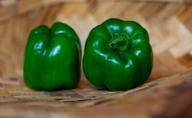 Fresh green capsicum vegetable on a bamboo background