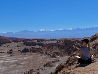Fototapeta na wymiar Blond young woman sitting and meditating in valley of the moon, Atacama, Chile
