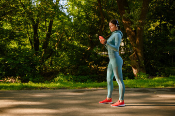 Fototapeta premium Training in park, smiling woman in headphones