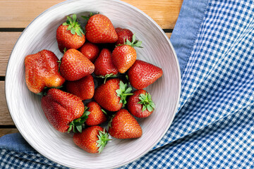 Delicious juicy strawberries on the plate with wooden background.