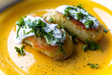 Potato patties (zrazy) stuffed with onion and mushrooms, served with greenery (cilantro), spices and cream sauce. 