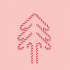 Funny Christmas tree made of candy cane on a pink background. Creative modern minimal composition. Concept of celebration Christmas and New year. Flat lay, top view, copy space