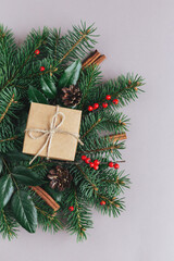Christmas background with spruce branches, red berries, cones, cinnamon sticks and craft gift box. Holiday eco-friendly concept.