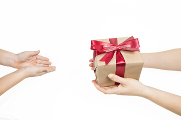 women's hands hold out a gift box with a red ribbon to children's hands on a white background