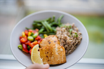 Hand holding salmon and buckwheat dish with green beans