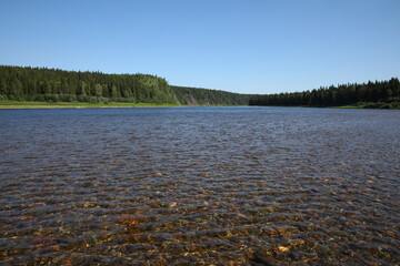 Water landscape.Panoramic view of the lake with clear pure water with pebbles on the bottom and forest on the shore.Untouched expanses of pristine nature.Ecological places in Russia