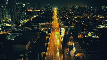 Night illuminated cityscape with traffic highway at business centre aerial. Epic twilight city in...
