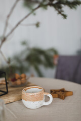 Ceramic beige coffee cup on a table with beige linen tablecloth. Scandinavian interior.