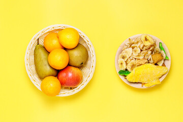 Assortment of dried and raw fruits on a yellow background, healthy food concept