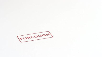Putting red FURLOUGH rubber stamp on the paper, close-up shot