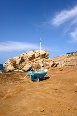 Blue boat on rocky coast of Koumbara beach located on Ios Island. Greece