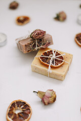Fototapeta na wymiar natural homemade soap bars with orange slices and flowers on white background. Spa concept, body care products. top view. 
