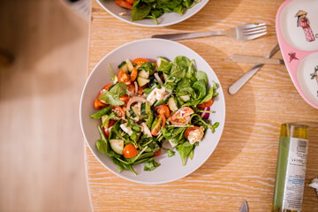Bowl of lettuce and tomato salad on a wooden table