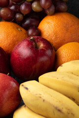 grapes tangerine bananas and apples on a dark pot