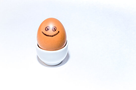 One single brown egg with positive face smiling stands in an egg holder on white background. Drawn black smile.